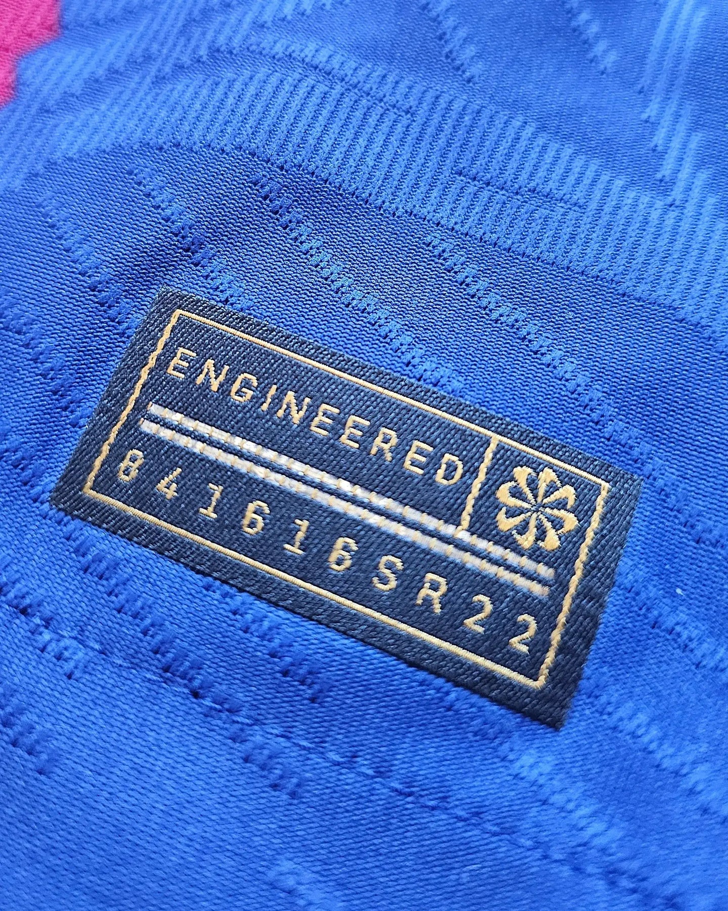 Close-up of the tag showing 'ENGINEERED' and the code '841616SR22' on a blue fabric.