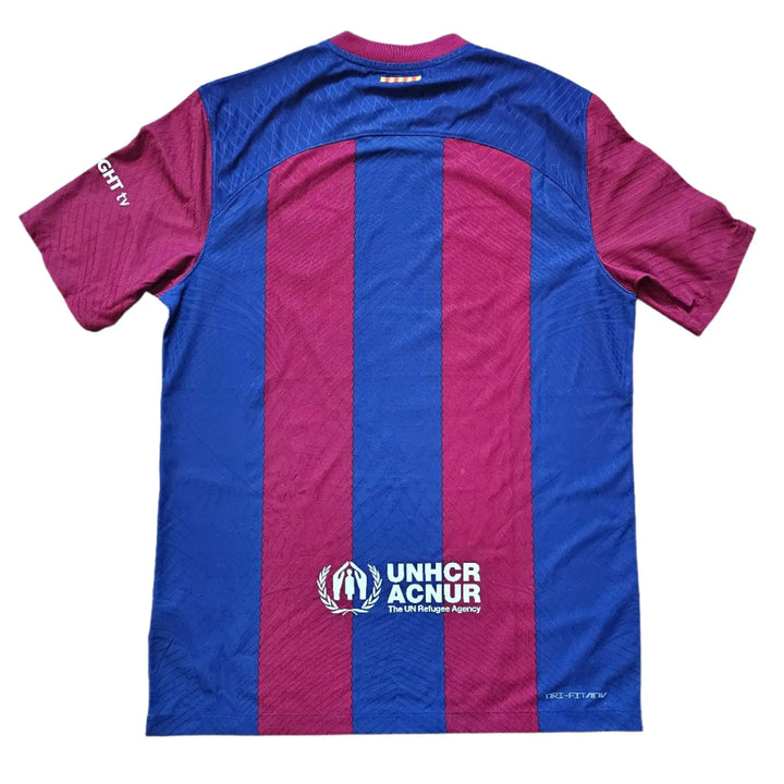 Back view of blue and red Barcelona 2024 ROLLING STONES shirt featuring UNHCR logo.