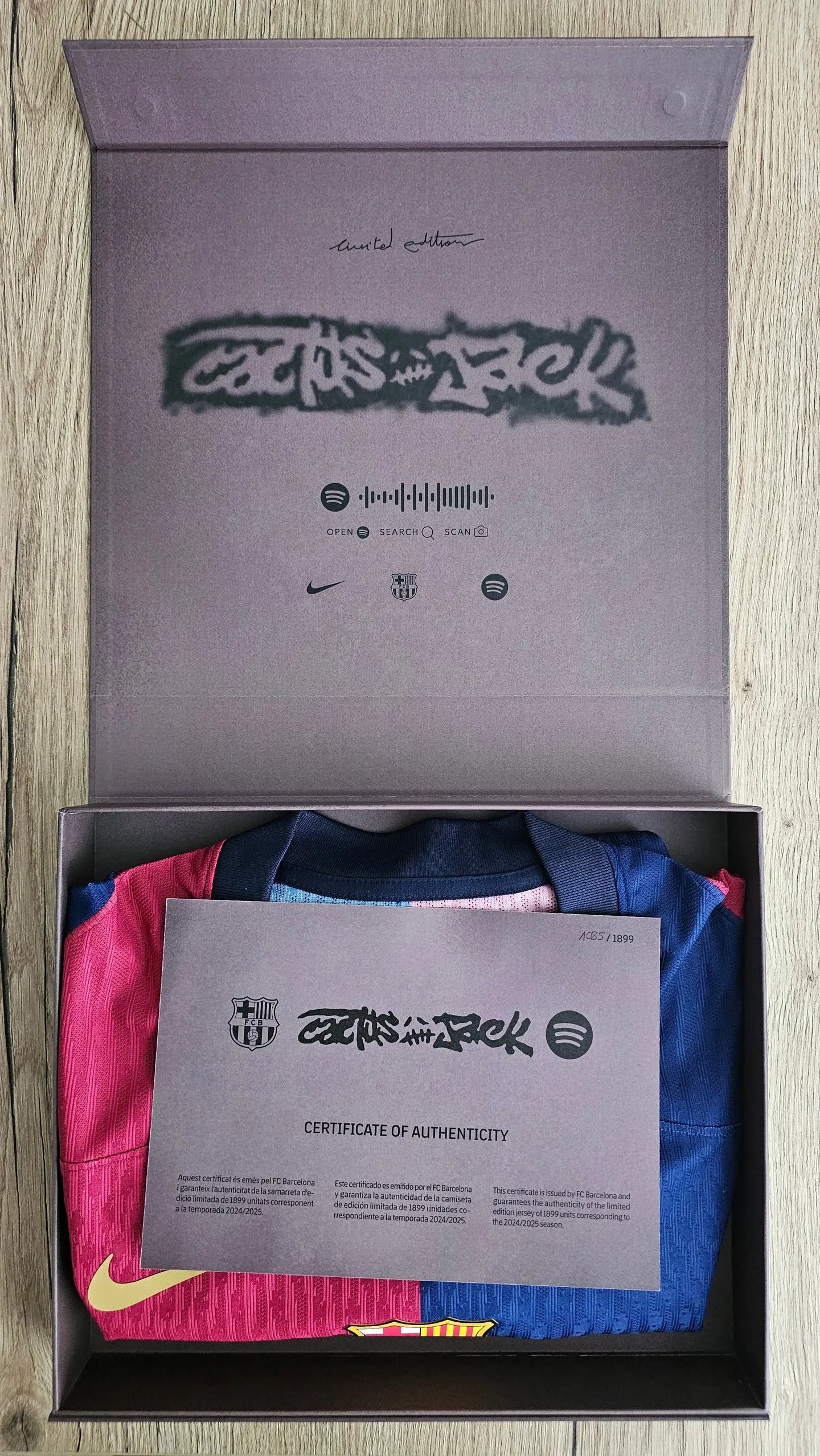 Box containing a Barcelona football shirt with a certificate of authenticity on a wooden surface