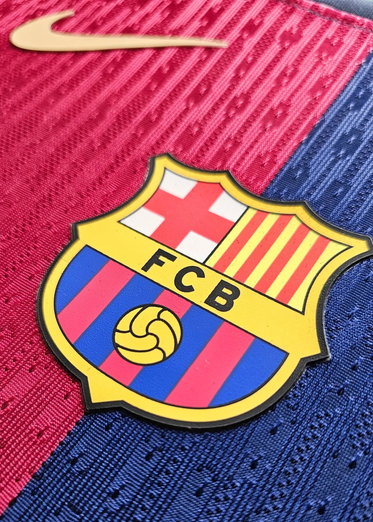 Detail of FC Barcelona crest featuring yellow, red, and blue with 'FCB' text.
