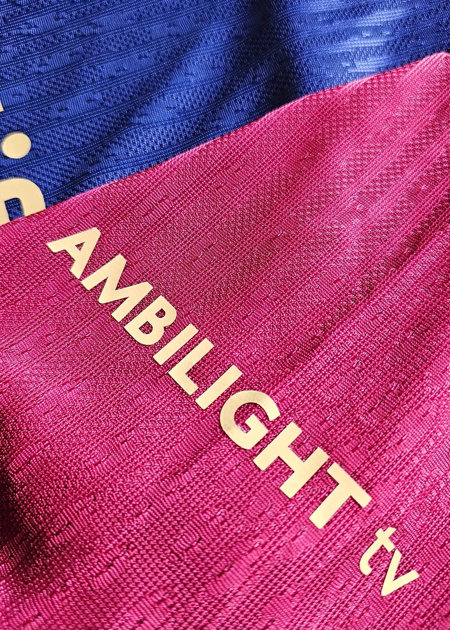 Detail showing the AMBILIGHT tv sponsor on a blue and red Barcelona football shirt.