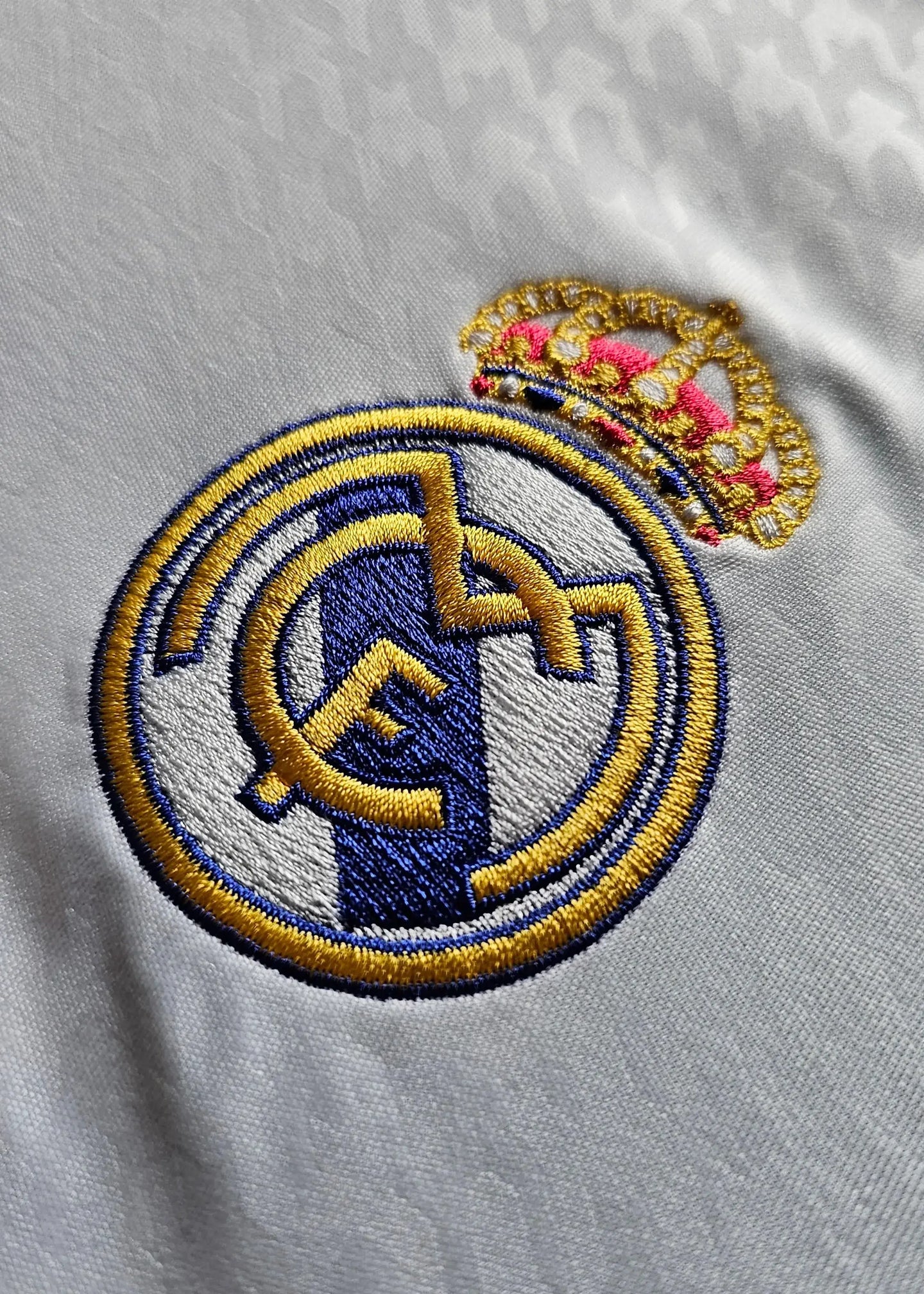 Close-up of the Real Madrid CF crest with gold and blue embroidery and crown detail.