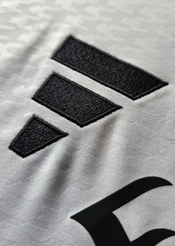 Close-up of the black adidas logo detail on the white Raúl Asencio 35 Real Madrid football shirt.