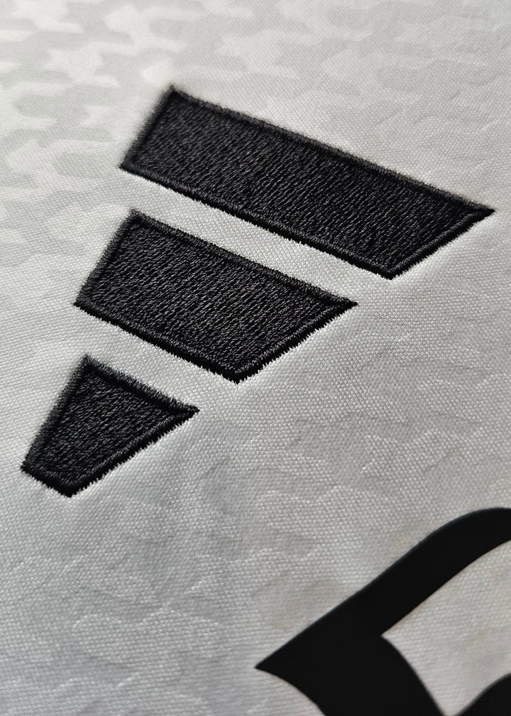 Close-up of the adidas logo on the white Real Madrid football shirt.