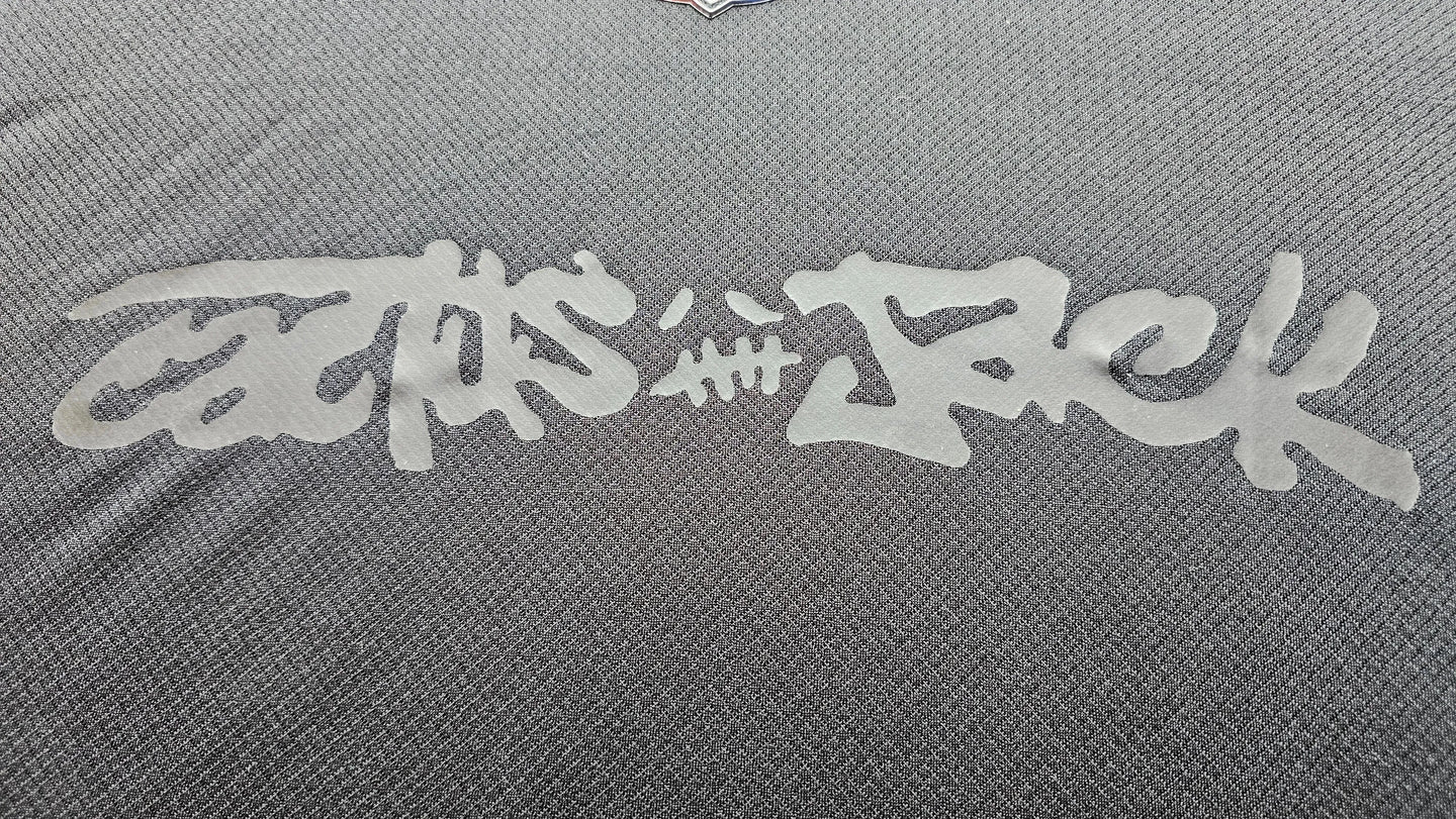 Close-up view showing signature detail of Travis Scott on FC Barcelona 2025 black football shirt.