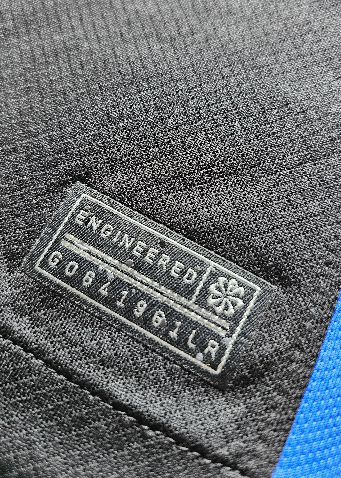 Close-up of the label showing 'ENGINEERED' and code 'G0641961LR' on the black football shirt.
