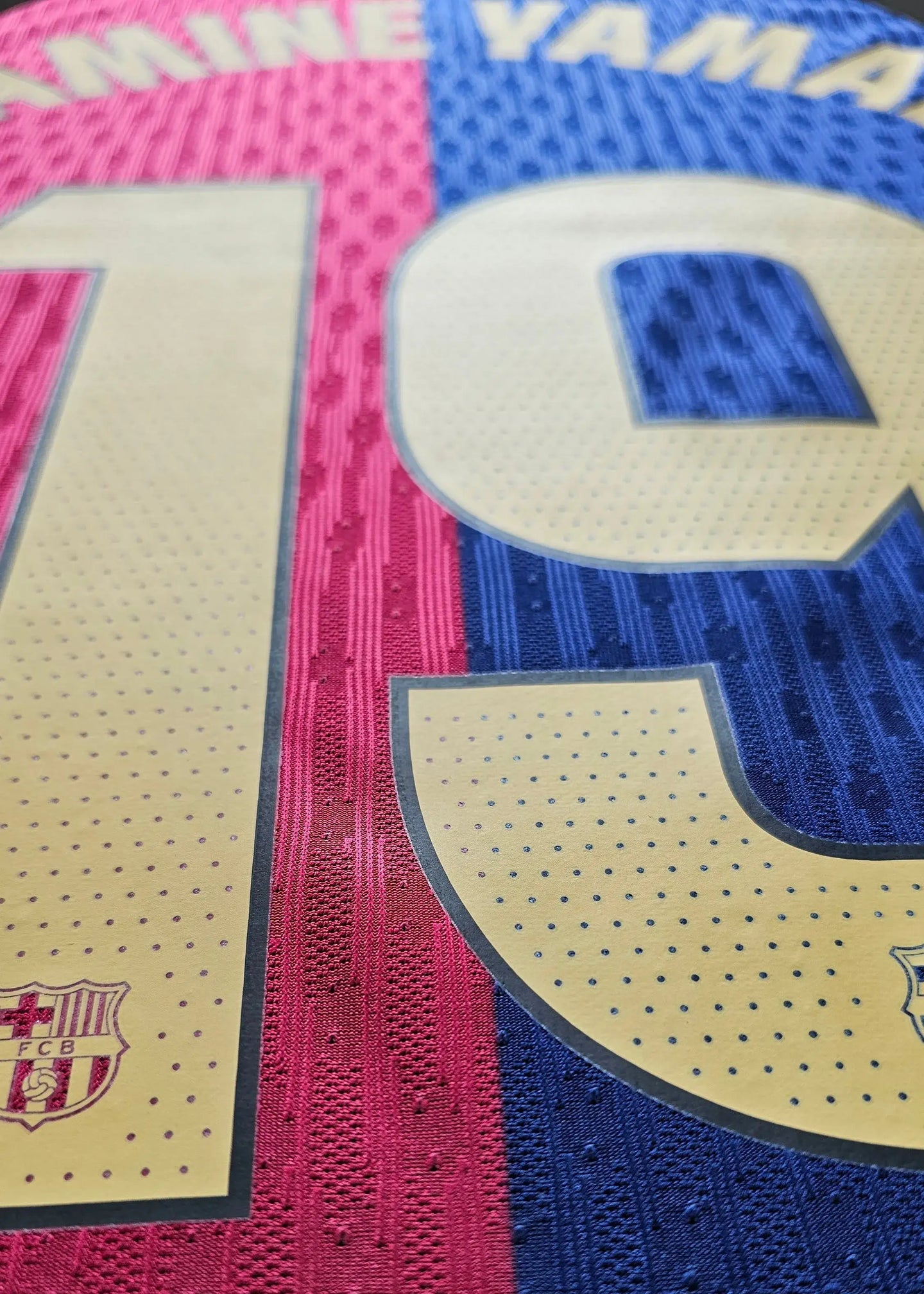 Detail view of No. 10 with name Yamal and FC Barcelona crest on pink and blue football shirt.