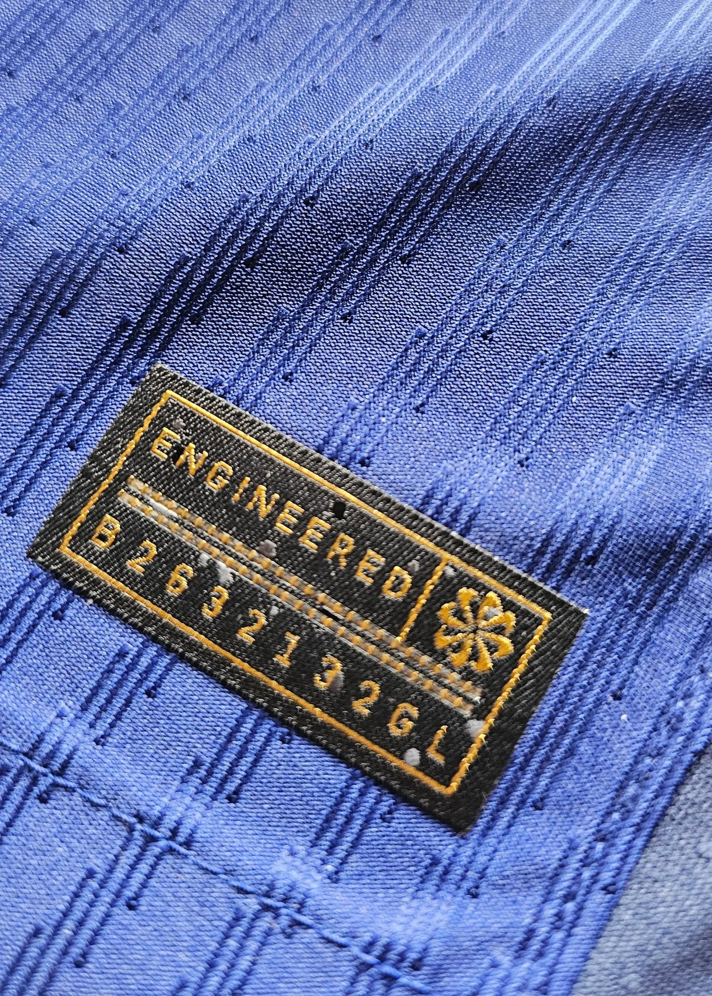 Detail view showing engineered tag with text 'ENGINEERED B2632132GL' on blue fabric.