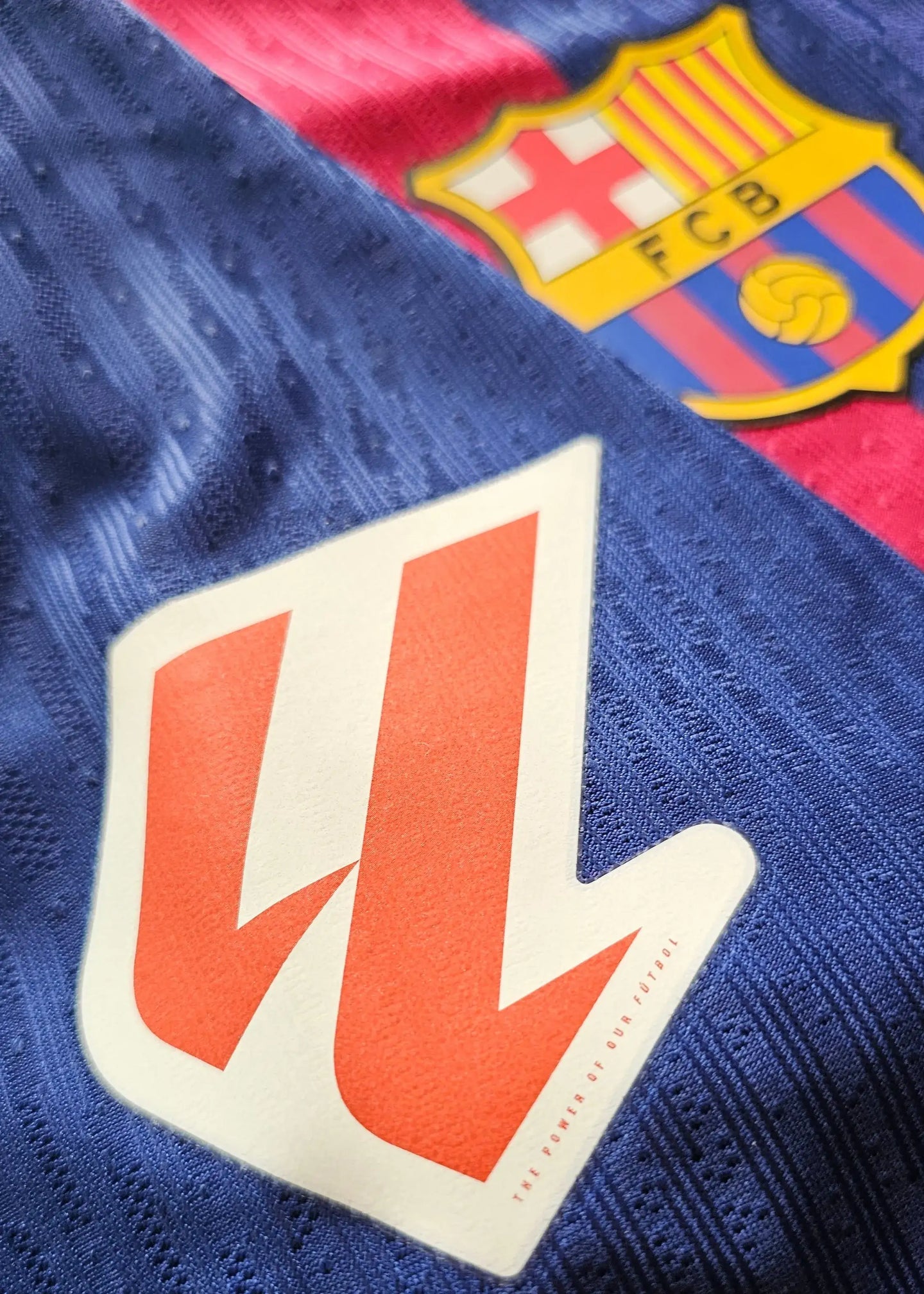 Close-up of FC Barcelona crest and TRAVIS SCOTT logo on the Lamine Yamal football shirt.