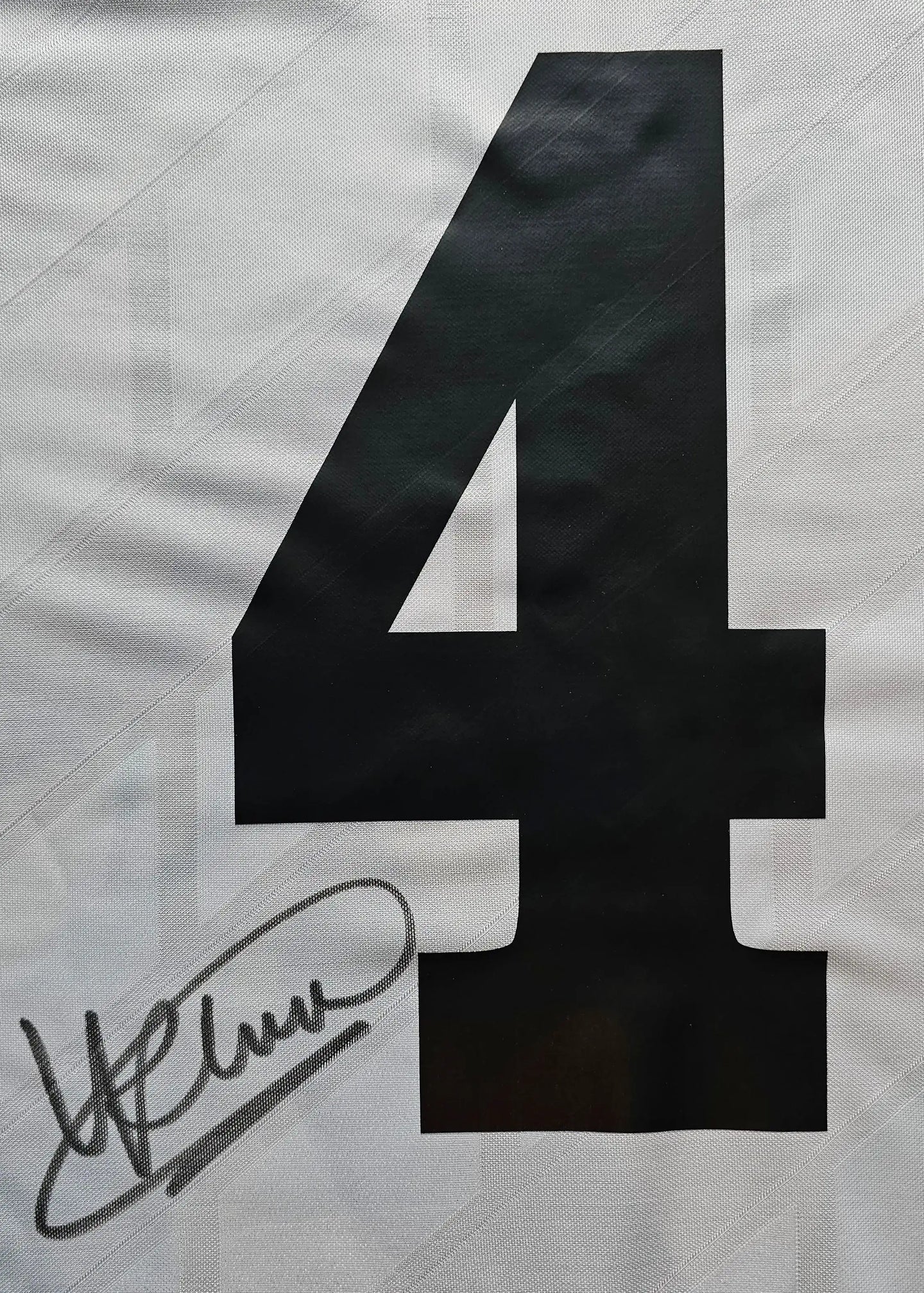 Close-up of No. 4 with signature detail on a white football shirt.