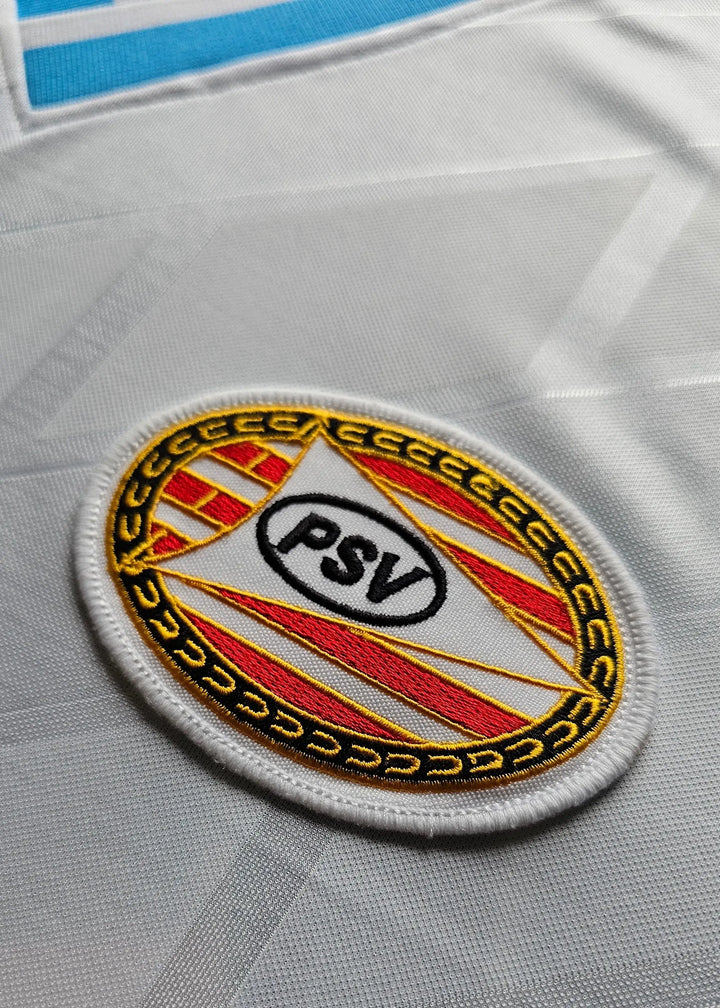 Crest detail showing the PSV badge featuring red and yellow stripes on a white background.