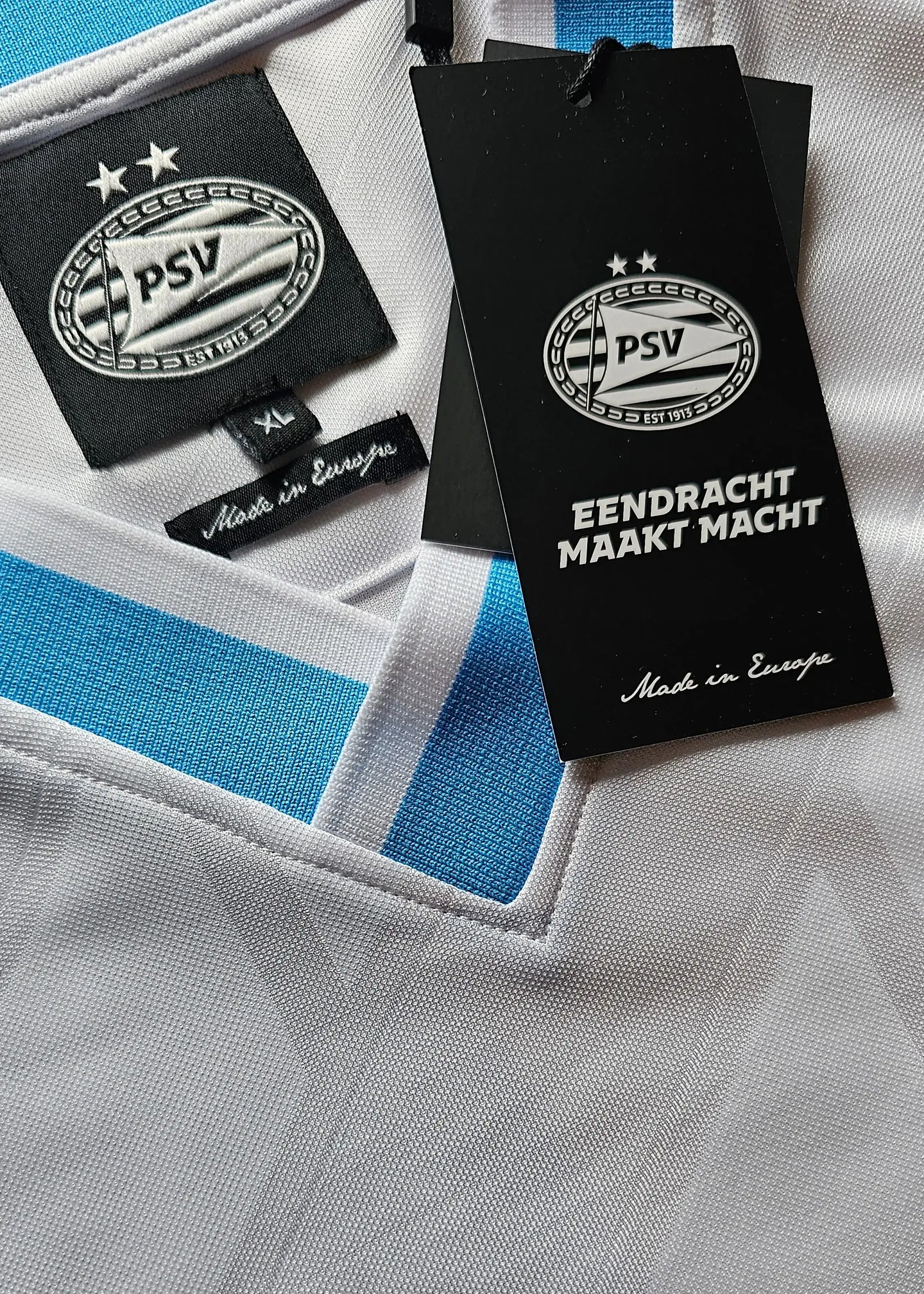 Crest detail showing PSV logo with two stars and the tag reading 'EENDRACHT MAKT MACHT'.