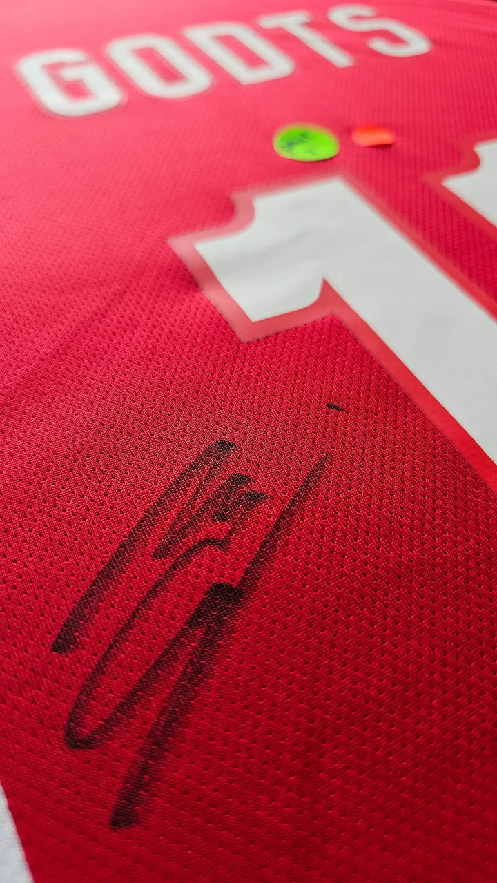 Close-up of Mika Godts signature on the No. 11 Ajax football shirt in red with white detailing.