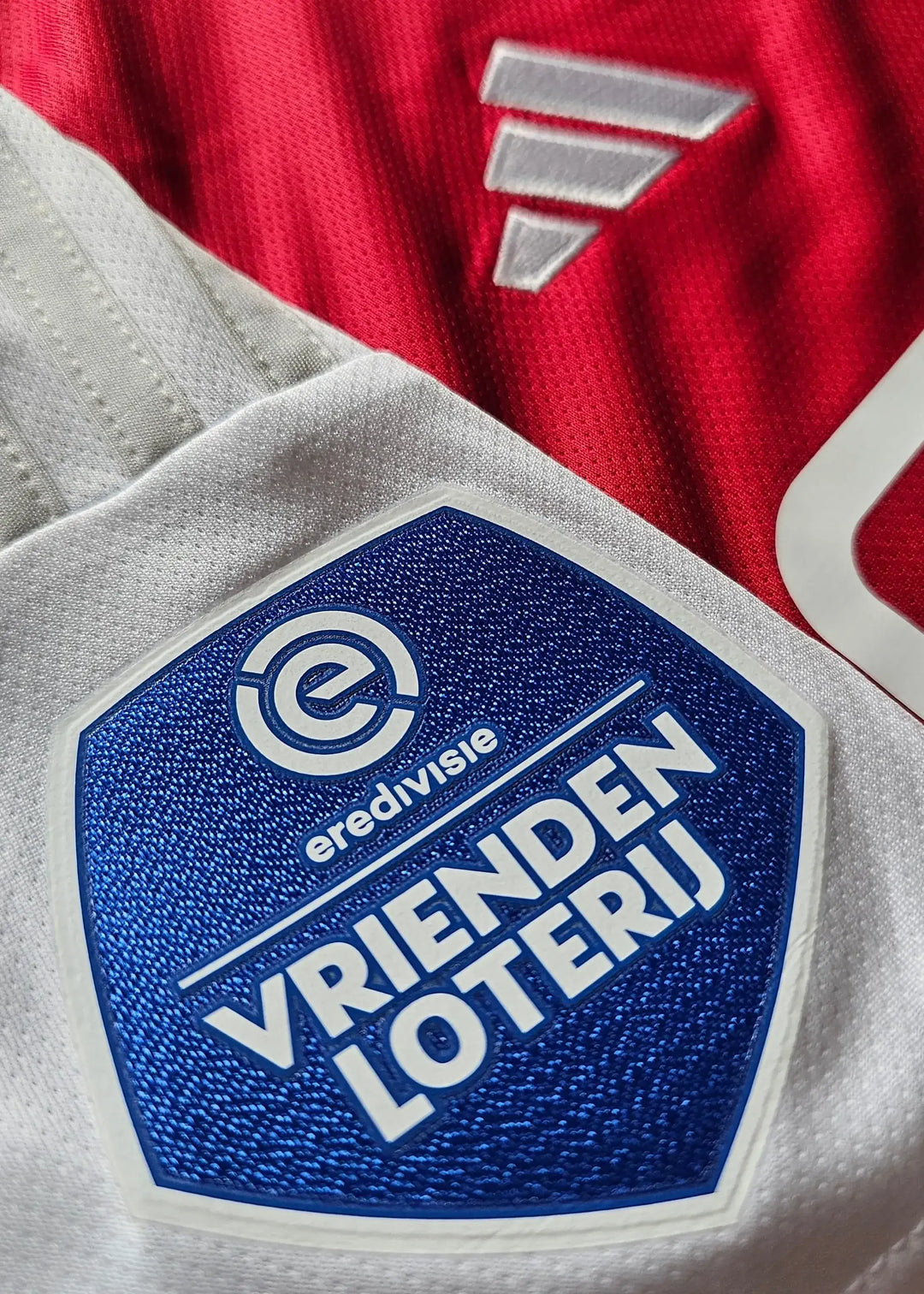 Close-up view of the AFC Ajax crest with 'VRIENDEN LOTERIJ' and 'eredivisie' on the sleeve.