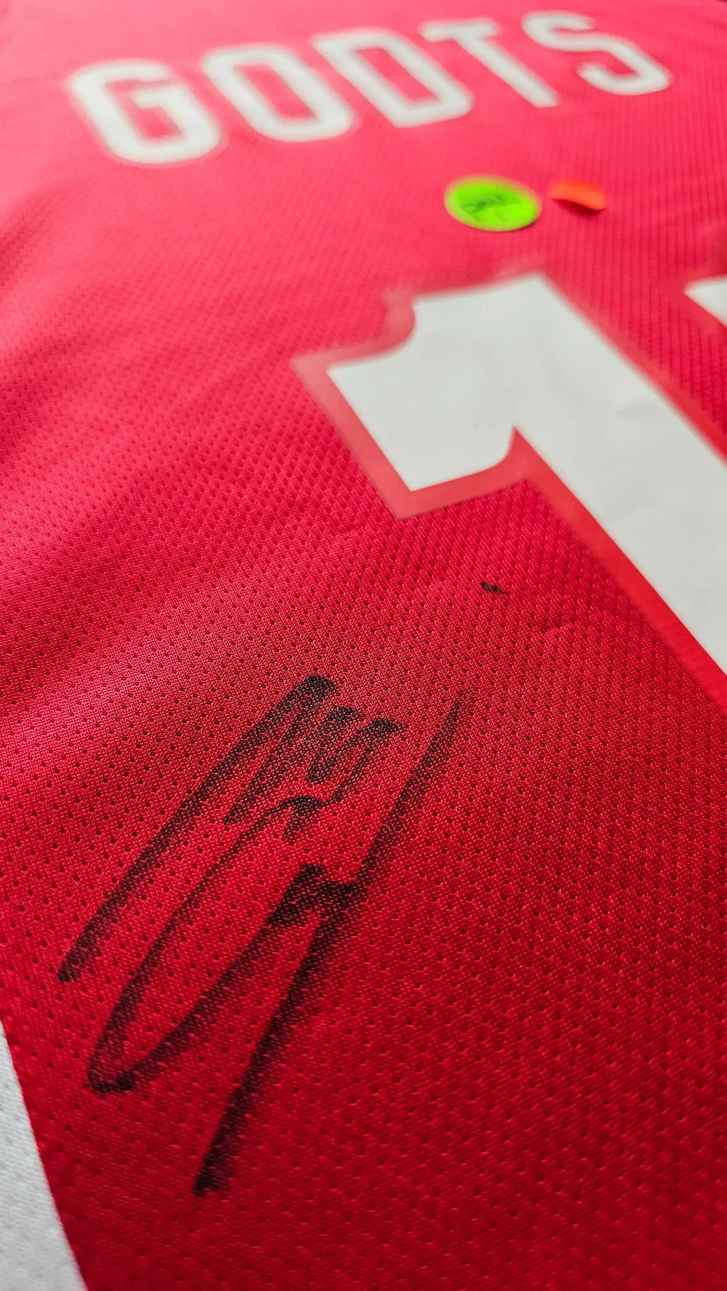 Detailed view showing the signature of Mika Godts on the red Ajax football shirt with number 11.