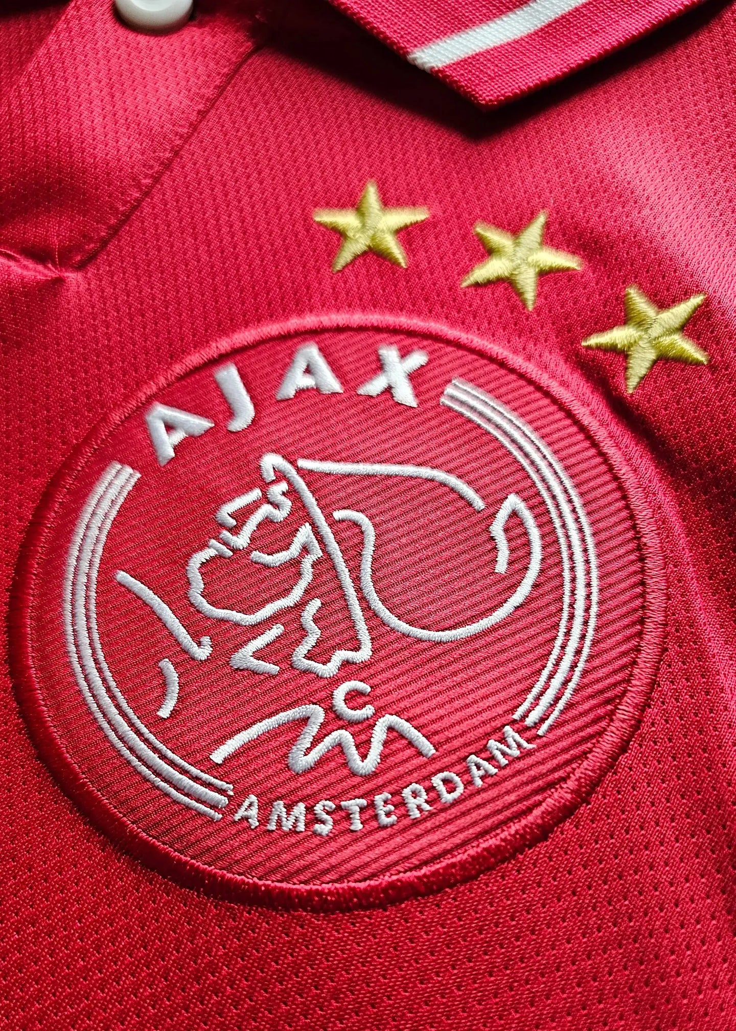 AJAX crest detail with three gold stars and embroidered text "AMSTERDAM".