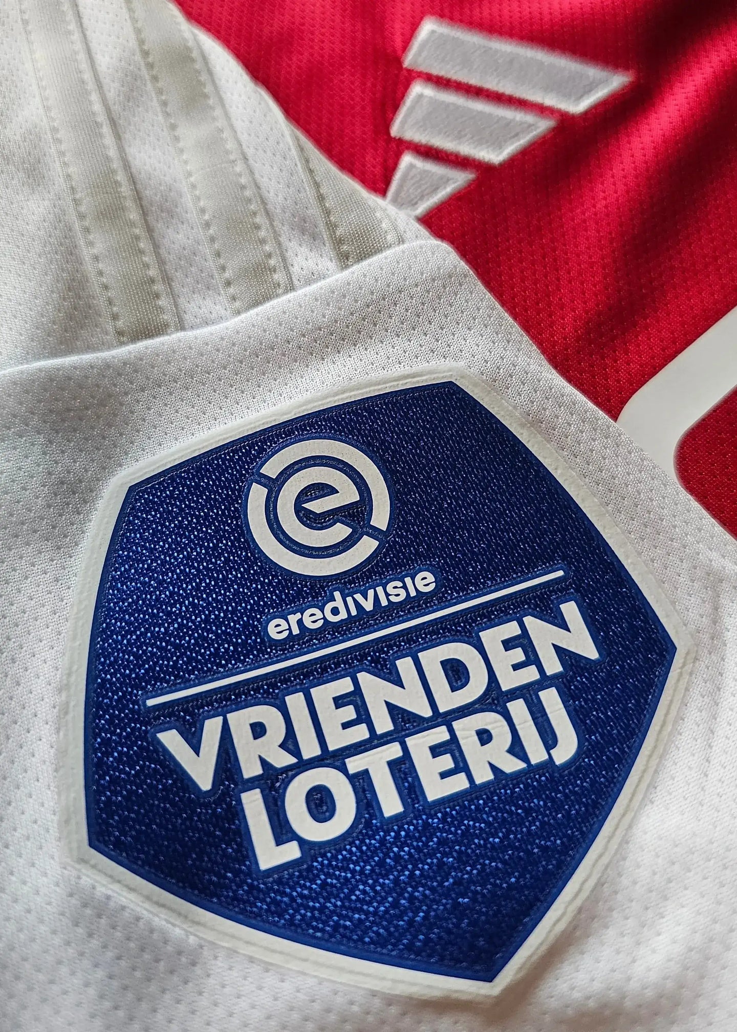 Detail showing the Vrienden Loterij crest and eredivisie branding on the Ajax football shirt.