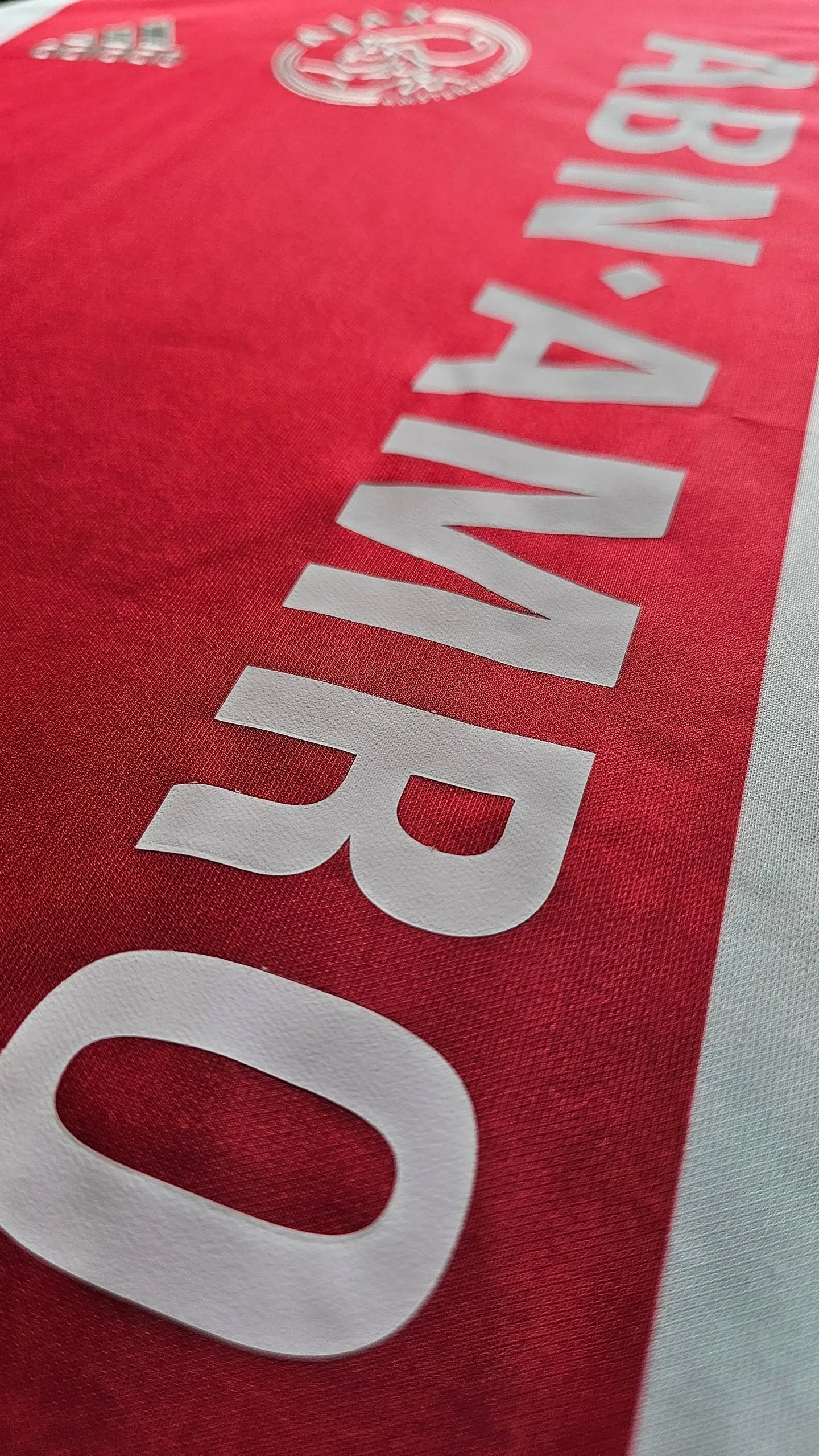 Detail view showing the ABN AMRO sponsor and Ajax crest on a red football shirt.