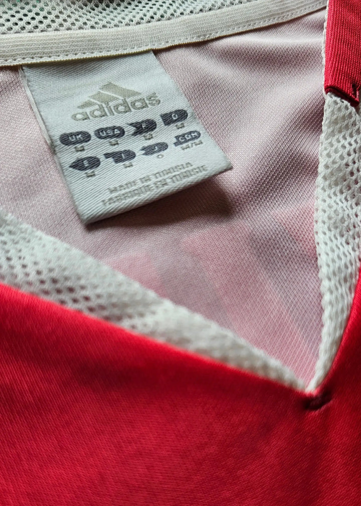 Size and care label showing adidas logo in a red and white Ajax shirt collar.