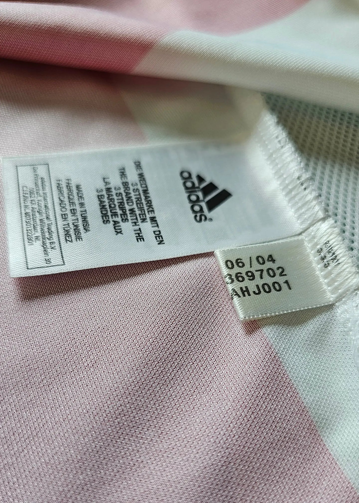 Visible adidas tag showing care instructions and product details on signed football shirt.