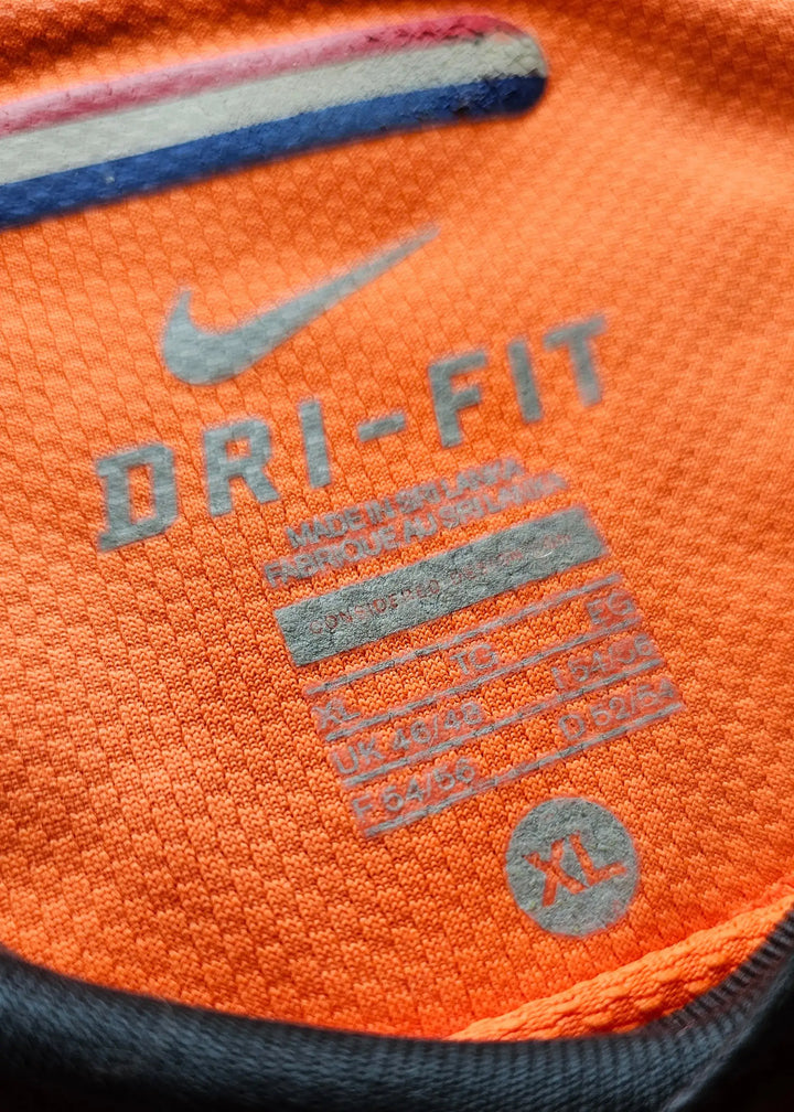 Close-up of size tag showing DRI-FIT, size XL, and care instructions on orange fabric.