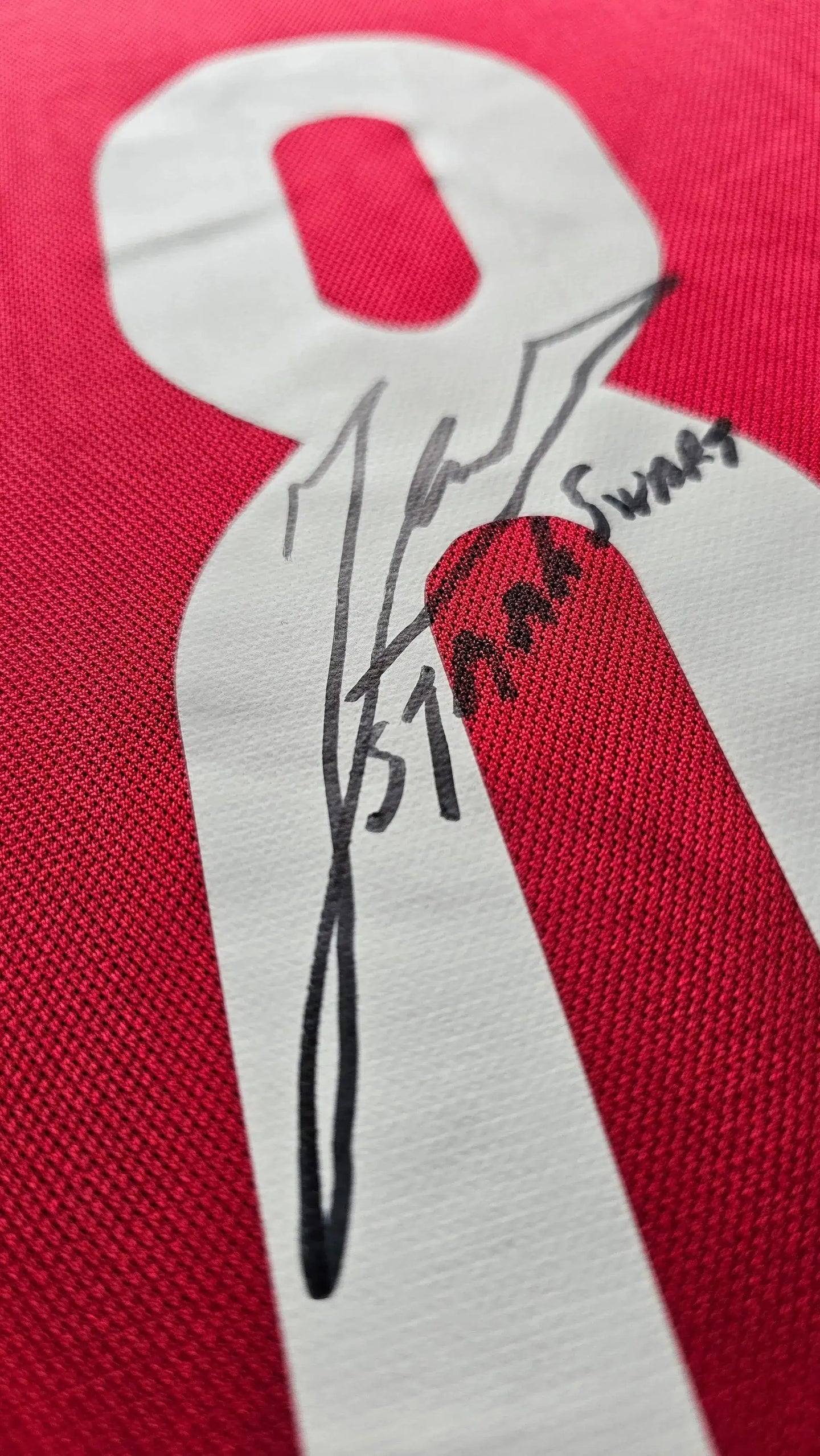 Detail view of No. 8 with signature of Sjaak Swart on red football shirt.