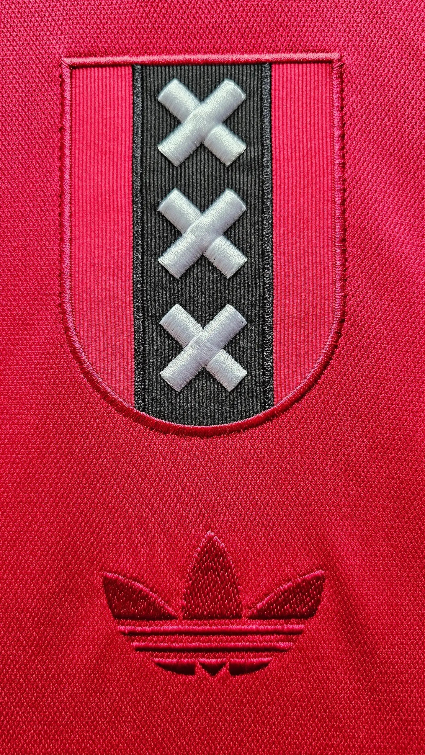 Crest detail featuring three white X's on a black strip and an embroidered Adidas logo.