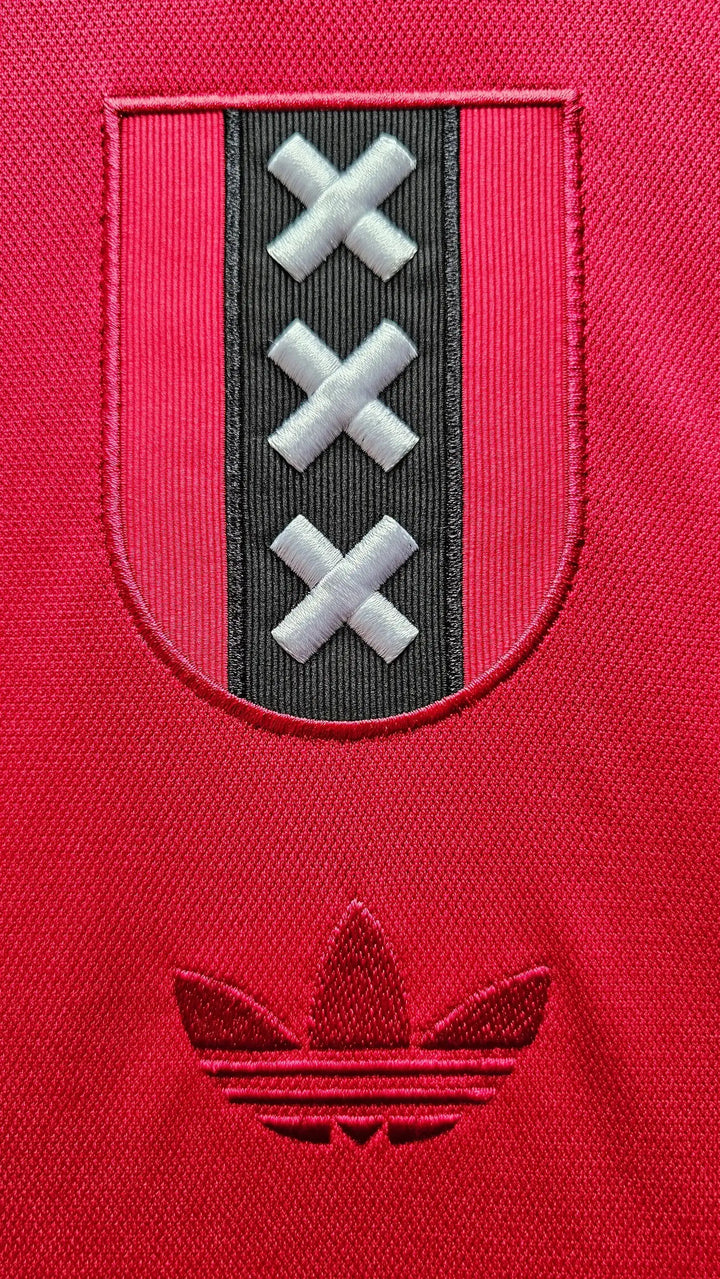 Crest detail featuring three white X's on a black strip and an embroidered adidas logo.
