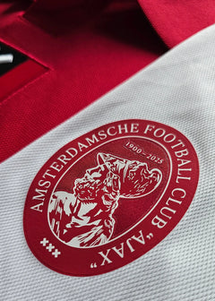 Detail showing the Ajax crest with the text 'AMSTERDAMS CHE FOOTBALL CLUB' and '1900-2025'.