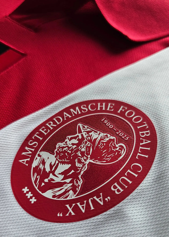 Crest detail showing AFC Ajax logo with text 'AMSTERDAMSCHE FOOTBALL CLUB' and dates '1900-2025'.