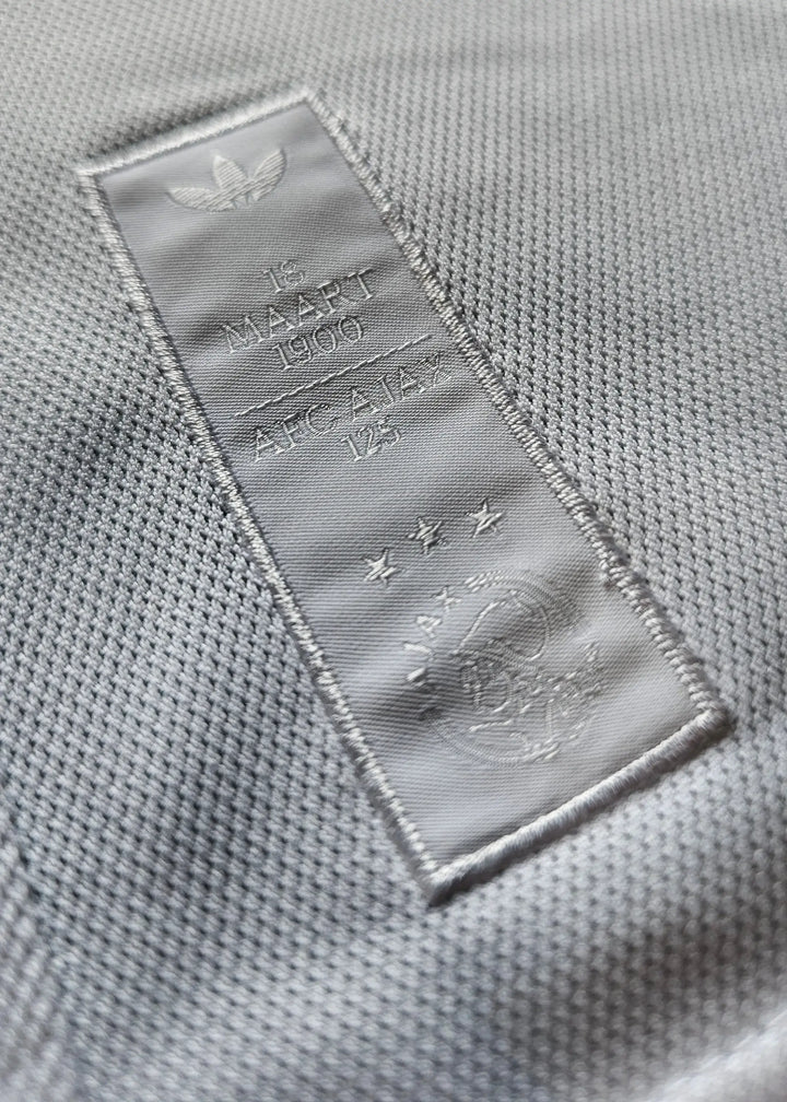 Detail showing AFC Ajax 125th Anniversary patch with three stars and embossed '18 MAART 1900'.
