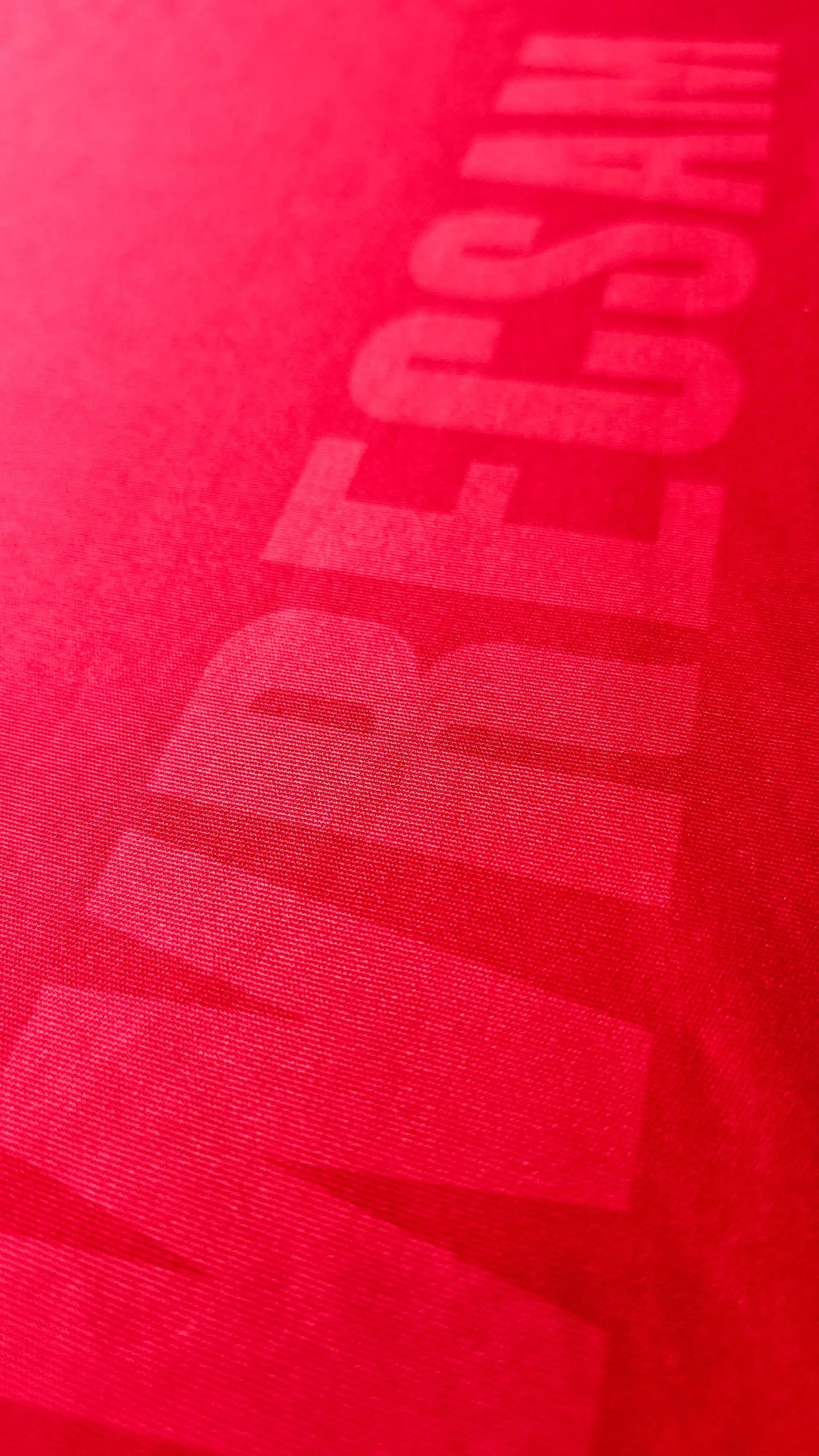 Close-up of the Wrexham AFC crest detail in red fabric with a textured finish.