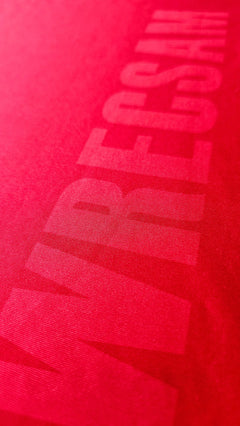 Close-up of the Wrexham AFC crest detail in red fabric with a textured finish.