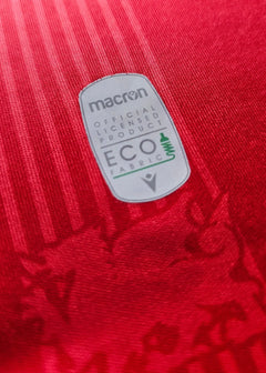 Crest detail featuring macron logo and ECO fabric label on red background.