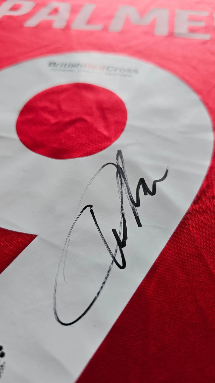 Close-up of signature on No. 9 Wrexham AFC soccer jersey by Ollie Palmer, featuring red color.