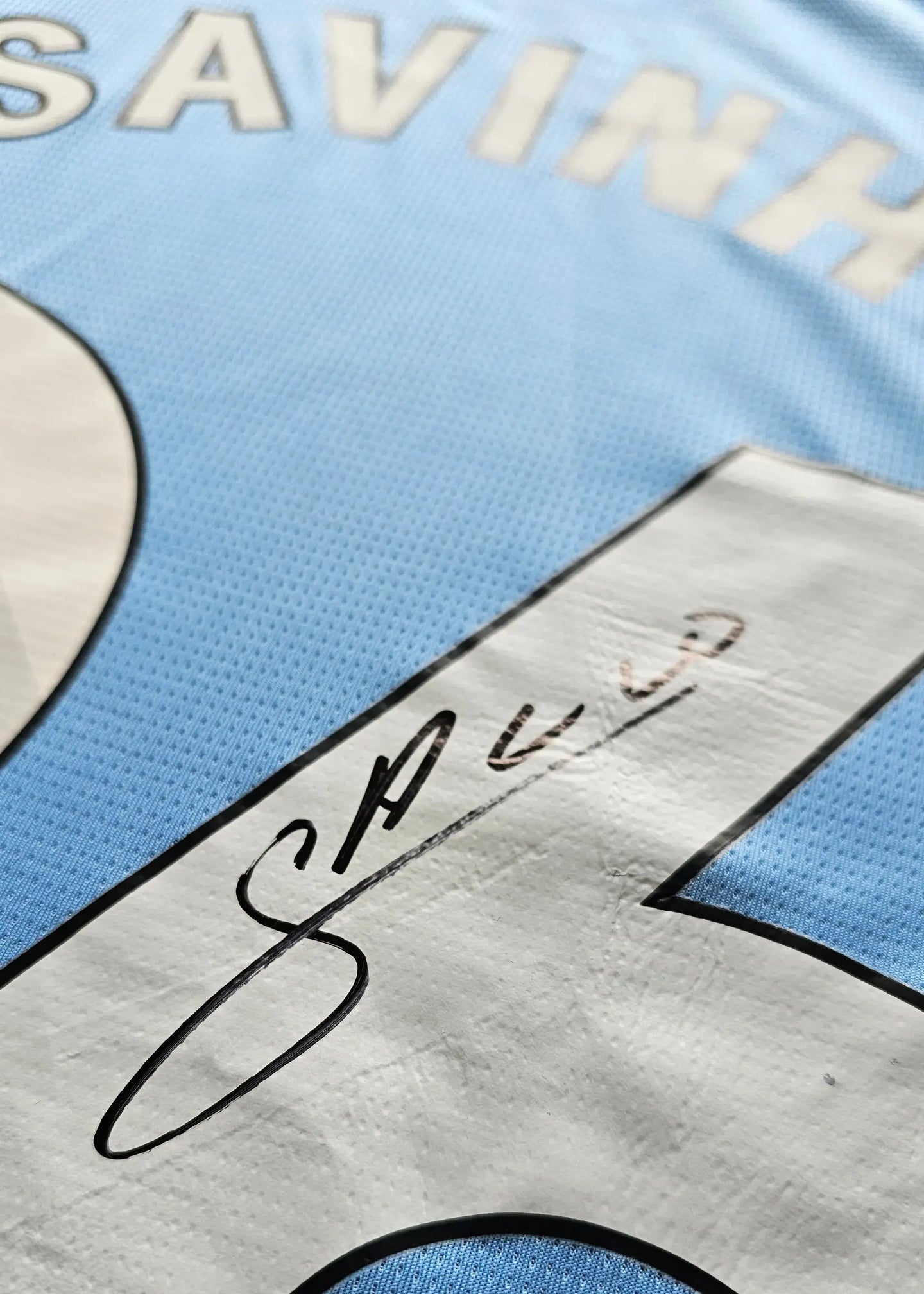 Close-up of Savinho's signature on Manchester City's No. 26 football shirt.