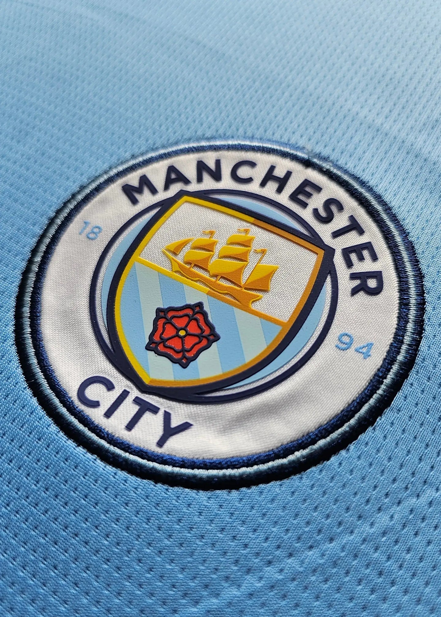 Detailed view of Manchester City crest, featuring ship design and rose emblem.