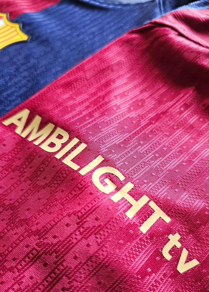 Detail view showing AMBILIGHT tv in gold on red fabric and blue crest of FC Barcelona.