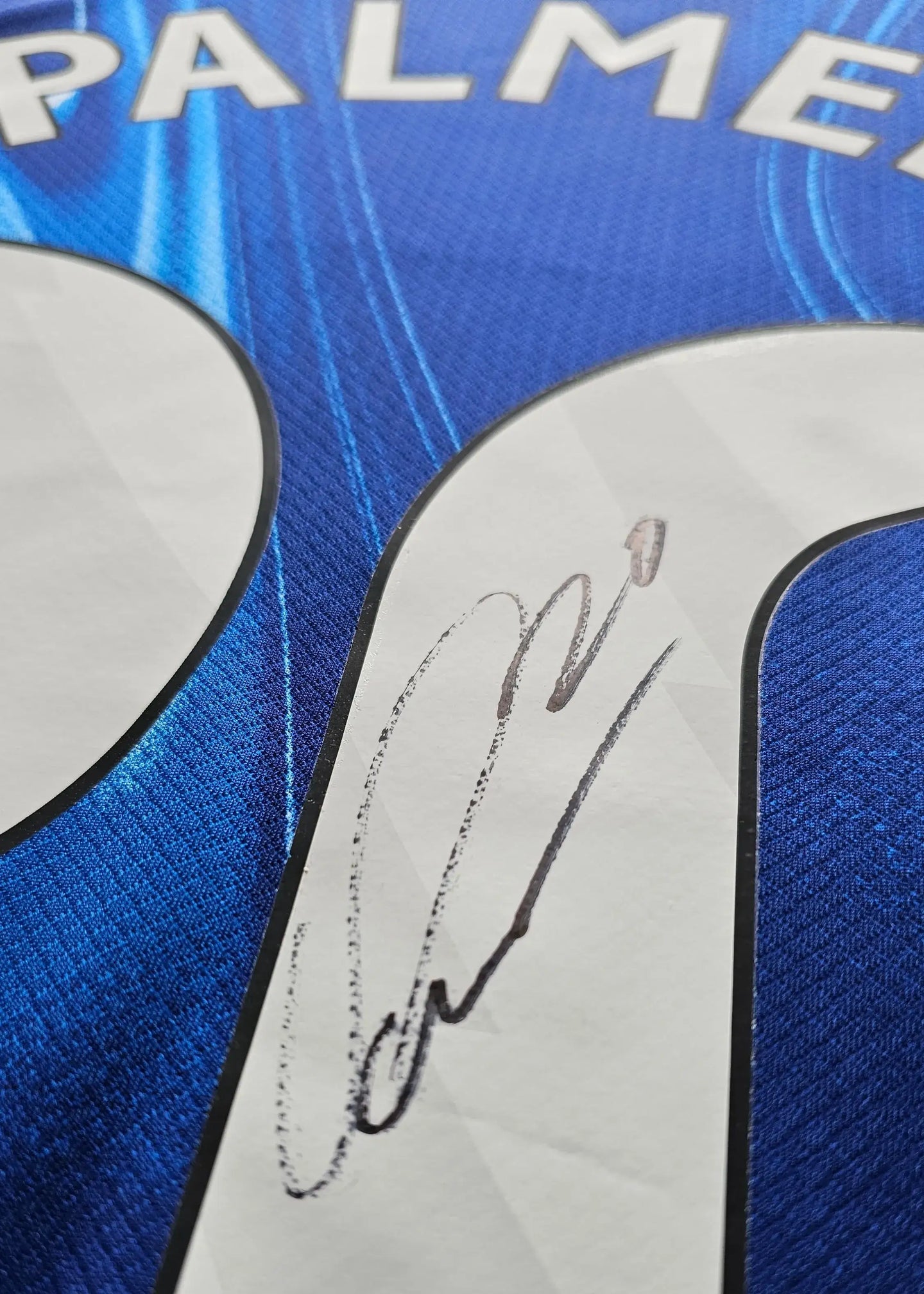 Close-up showing Cole Palmer's signature on the blue football shirt No. 20.