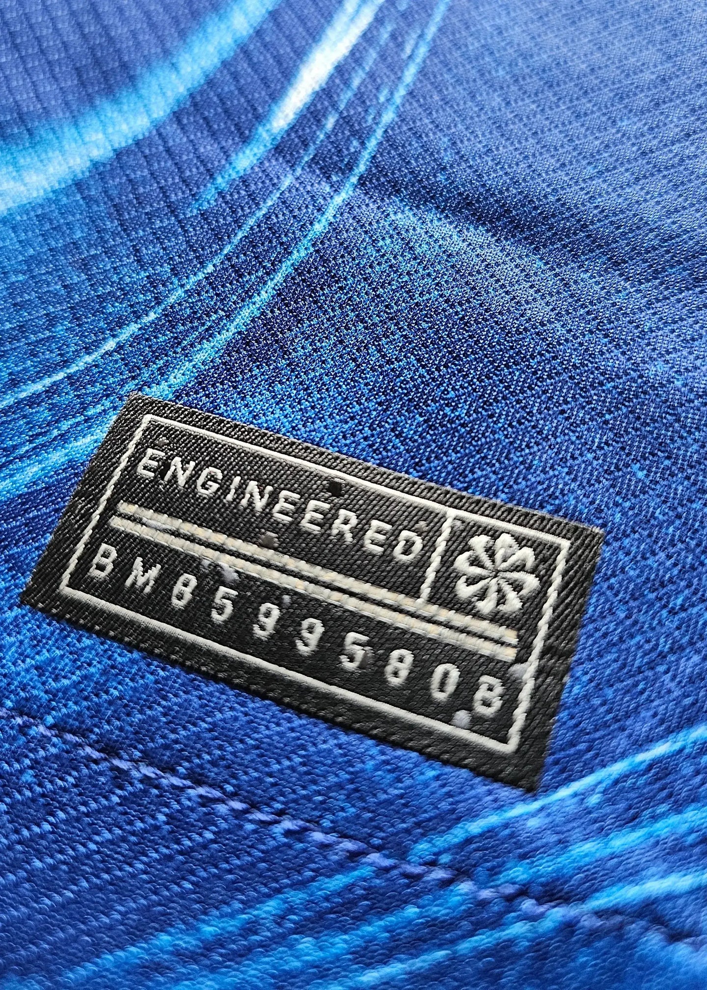 Close-up view of the care label detailing 'ENGINEERED' and 'BM85995808' on the blue fabric.