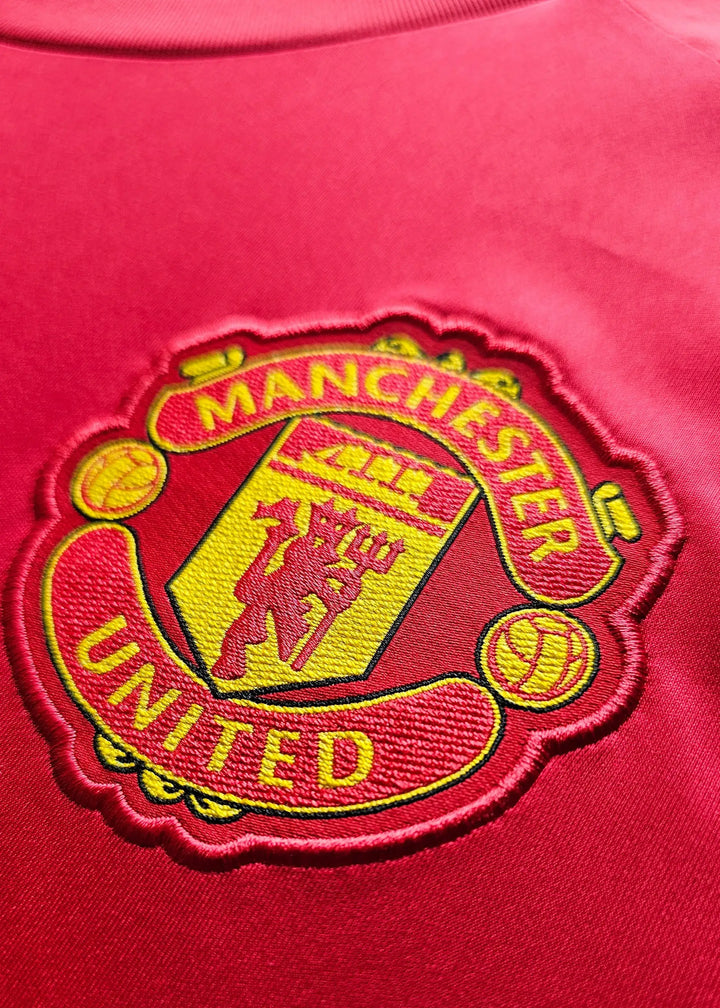 Close-up of the Manchester United crest featuring yellow stitching and details.
