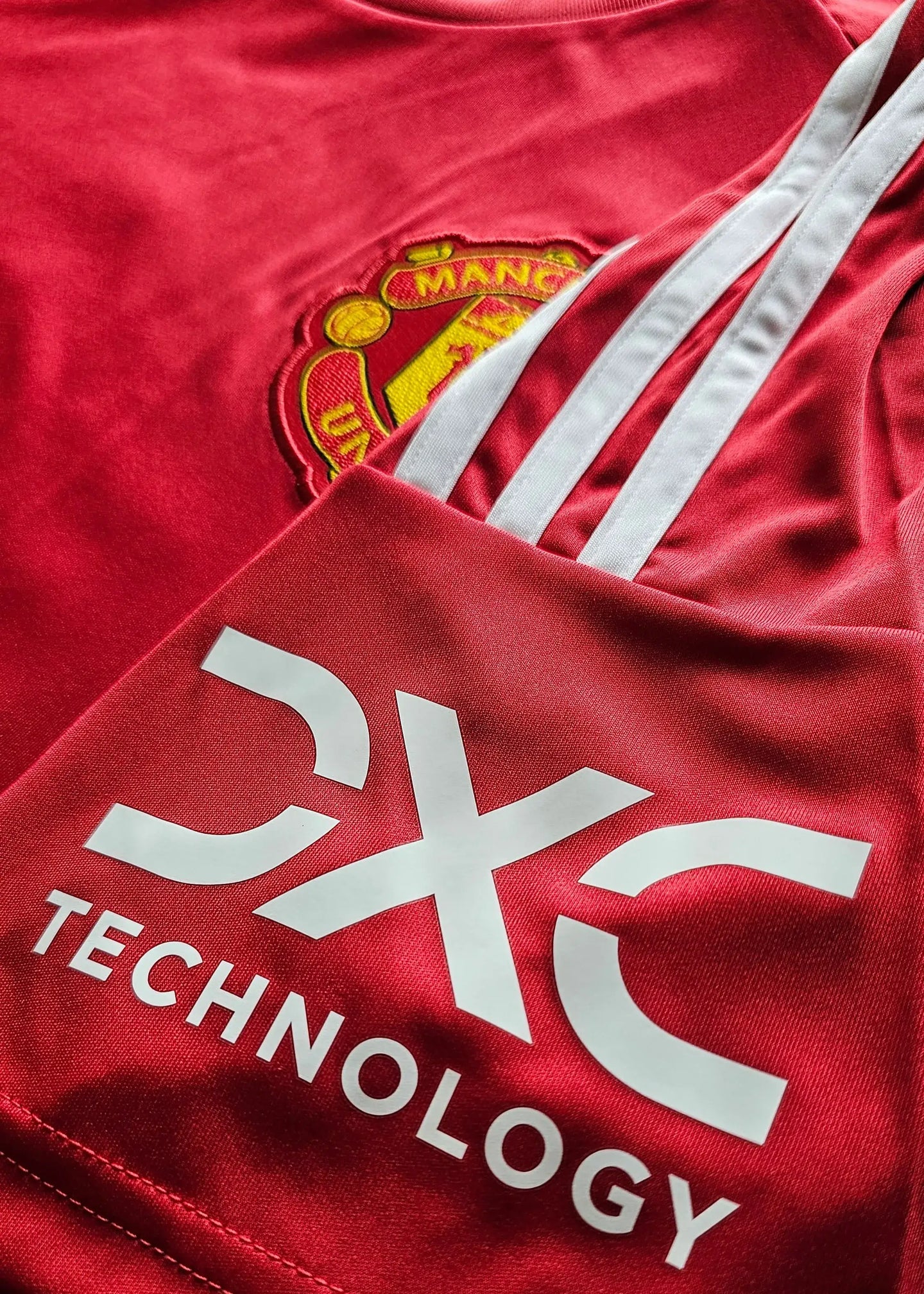 Close-up showing Manchester United crest and CX technology logo on a red football shirt.