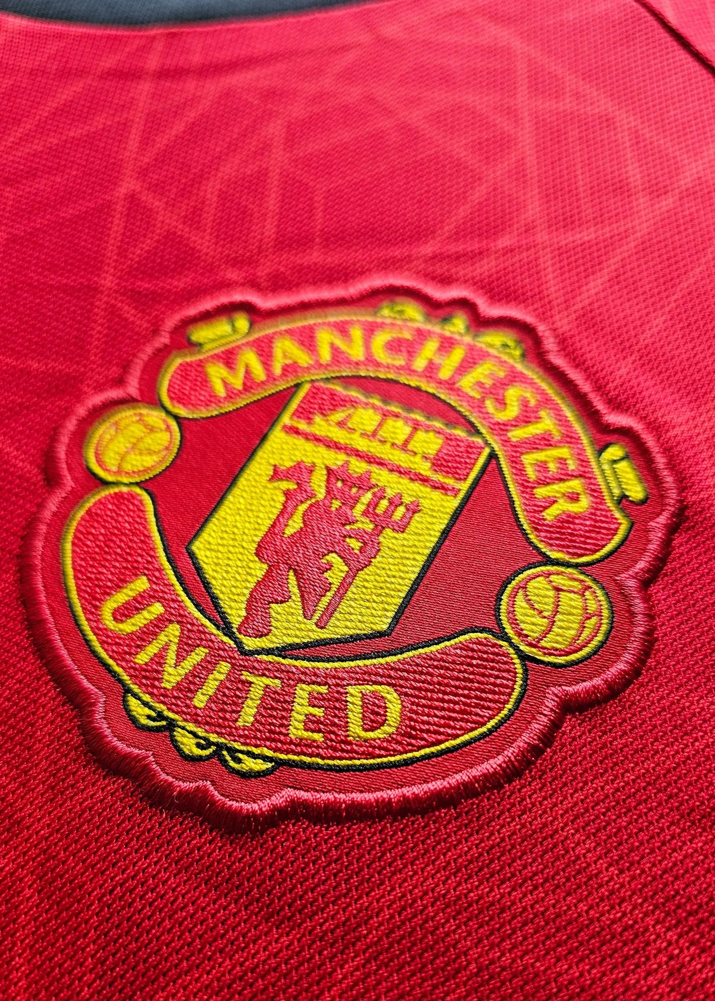 Close-up of Manchester United crest with yellow and red detailing.