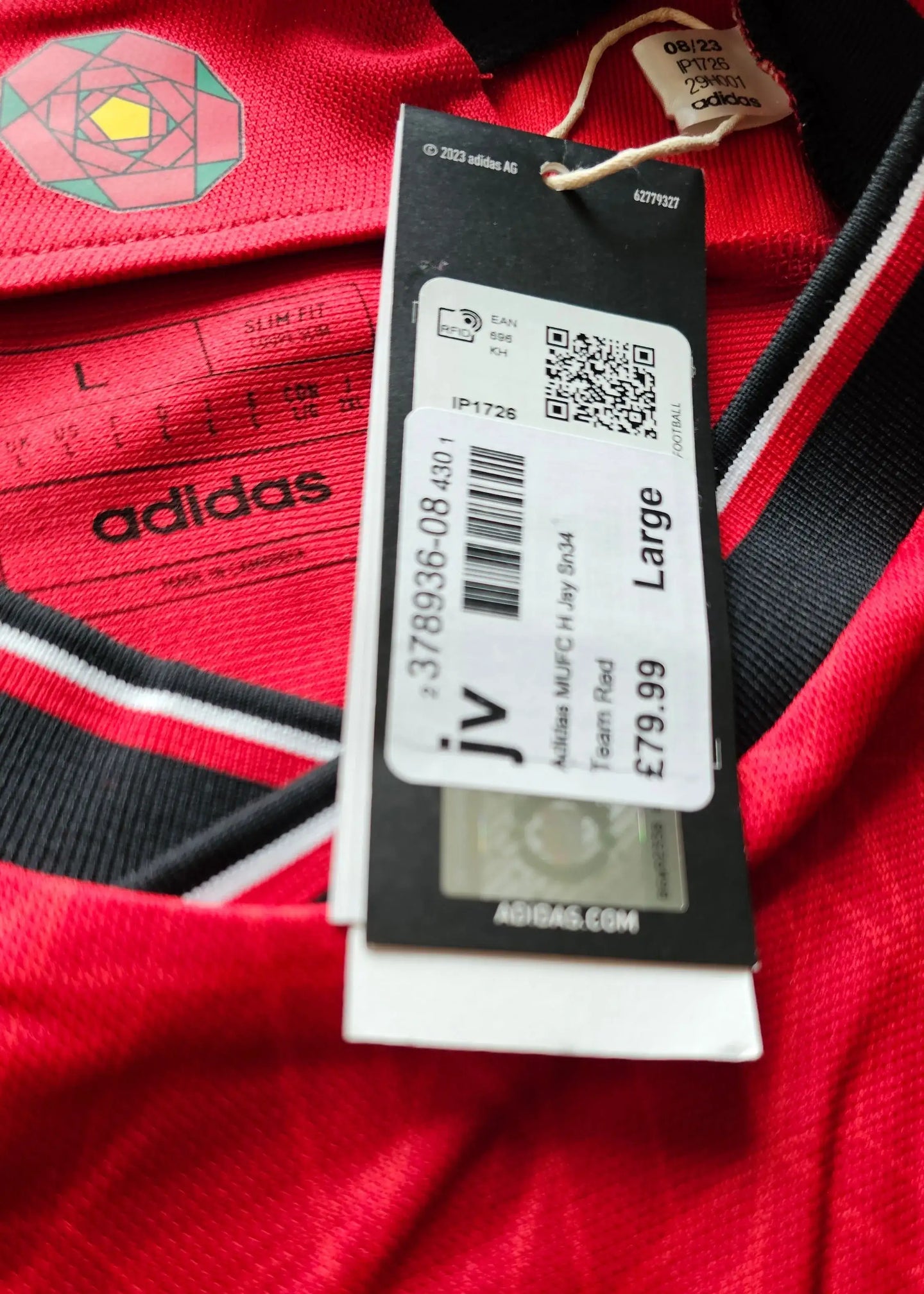 Close-up of red football shirt label showing adidas brand and size Large.