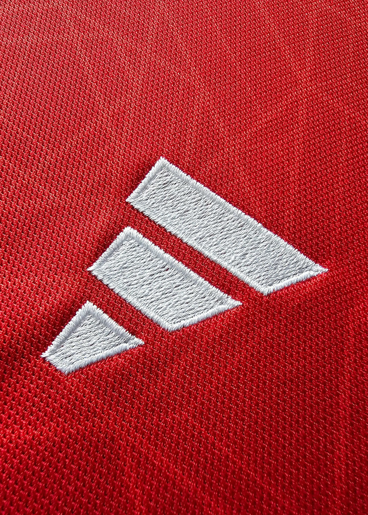 Close-up of white adidas logo on red fabric of football shirt.