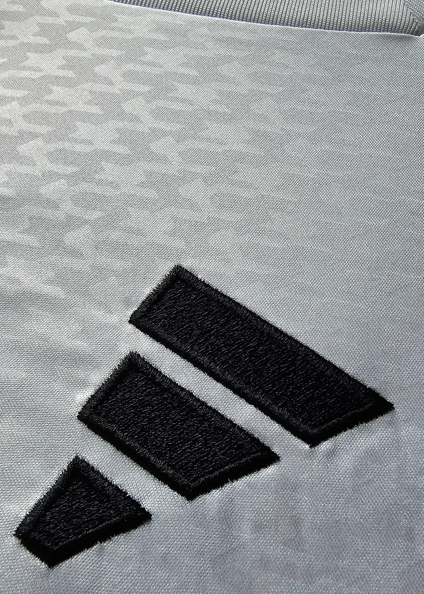 Close-up detail of black adidas wordmark on gray fabric.