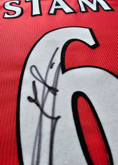 Detail view showing the signature of Stam over the No. 6 on a red football shirt.