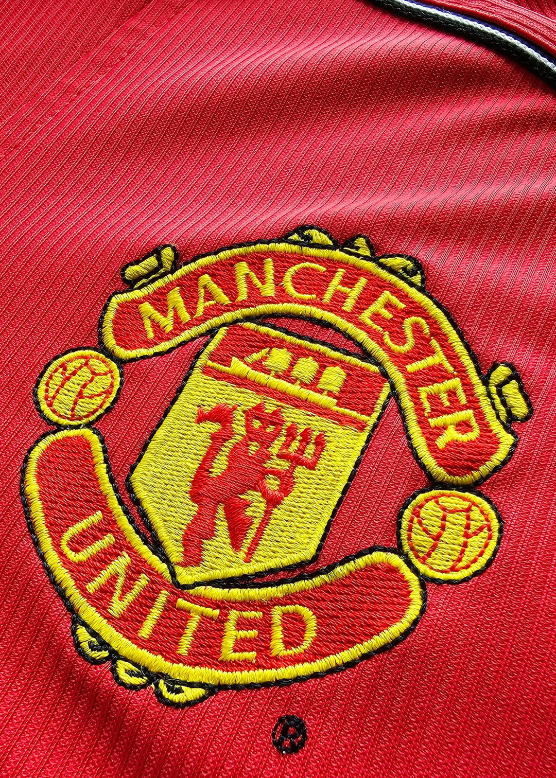 Close-up of the Manchester United crest with red and yellow embroidery detail.