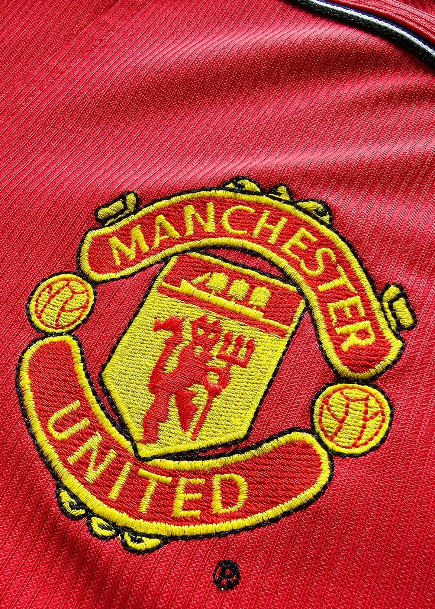 Close-up of the Manchester United crest featuring red and yellow embroidery details.