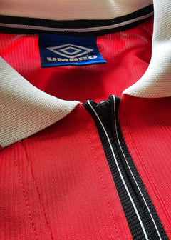 Close-up of collar and tag showing Umbro brand on red football shirt.